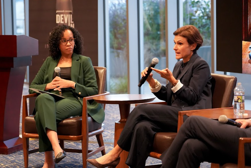Dr. Headley, wearing a forest green suit and glasses, sits attentively on a panel at the McCourt School of Public Policy during a 